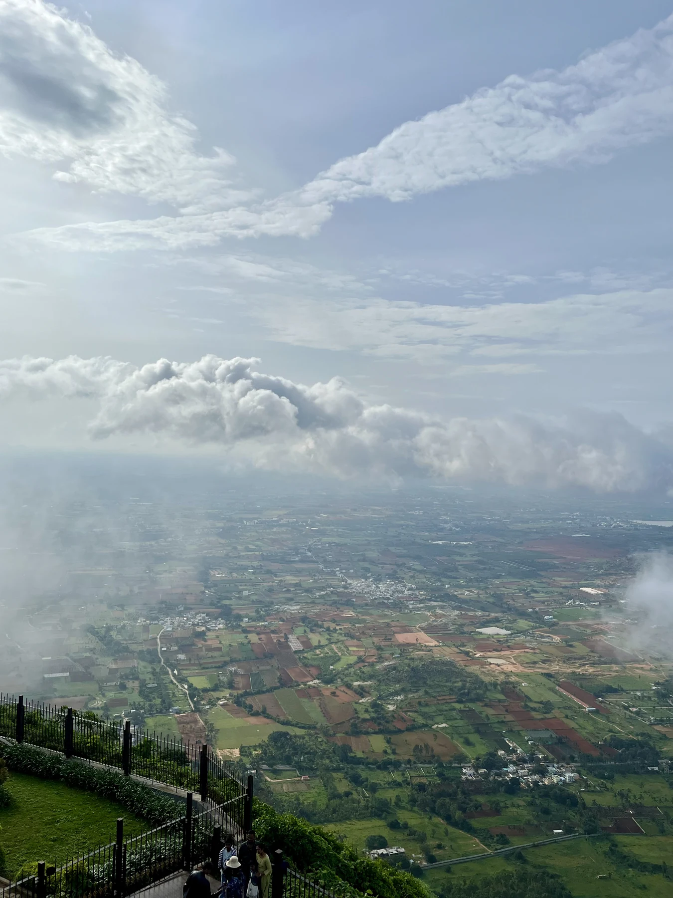 Hilltop view over green fields, half wrapped in clouds